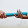 Photo of two people. One is handing a relay baton to the other person, symbolizing a succession plan.