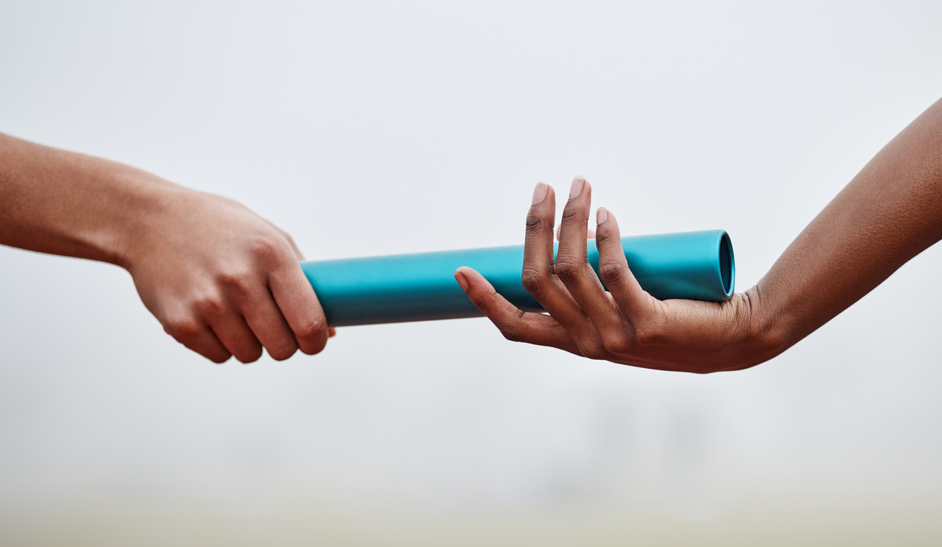 Photo of two people. One is handing a relay baton to the other person, symbolizing a succession plan.